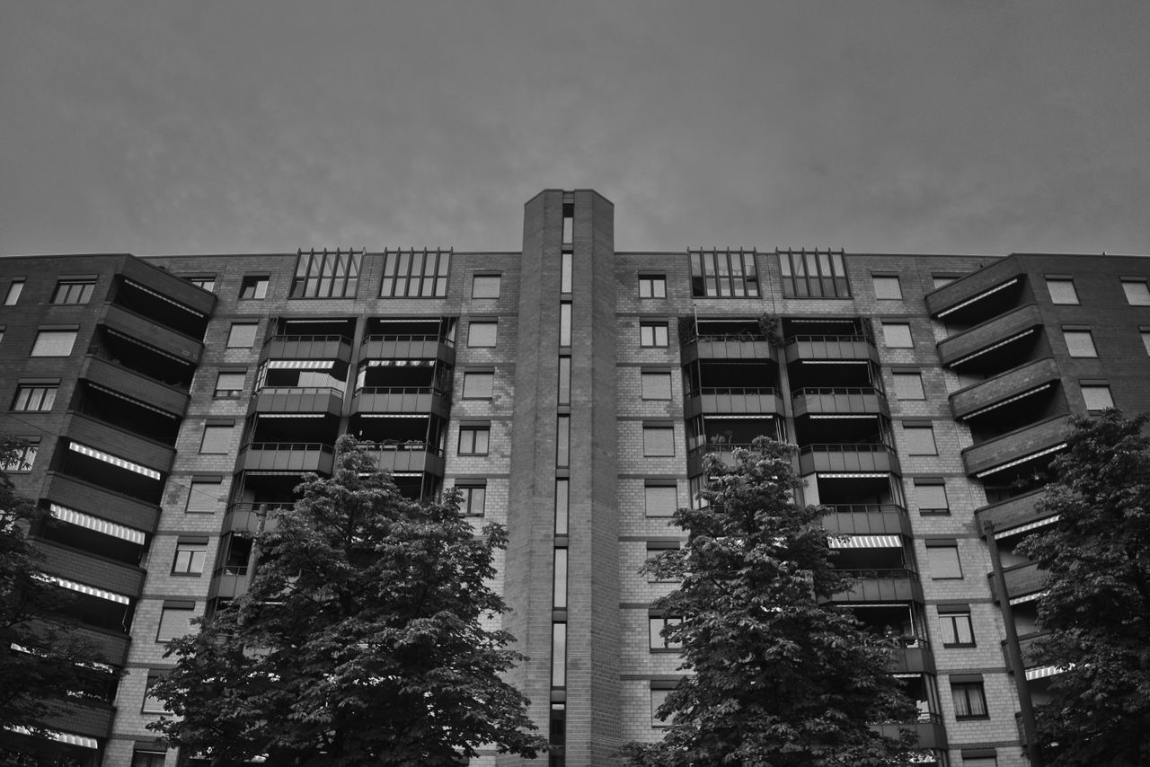 Crafting Captivating Headlines: Your awesome post title goes here Black and white photo of a modern apartment building facade with trees.