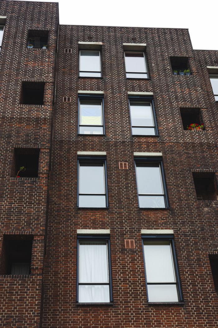 Vertical shot of a modern brick building facade with windows and architectural details.