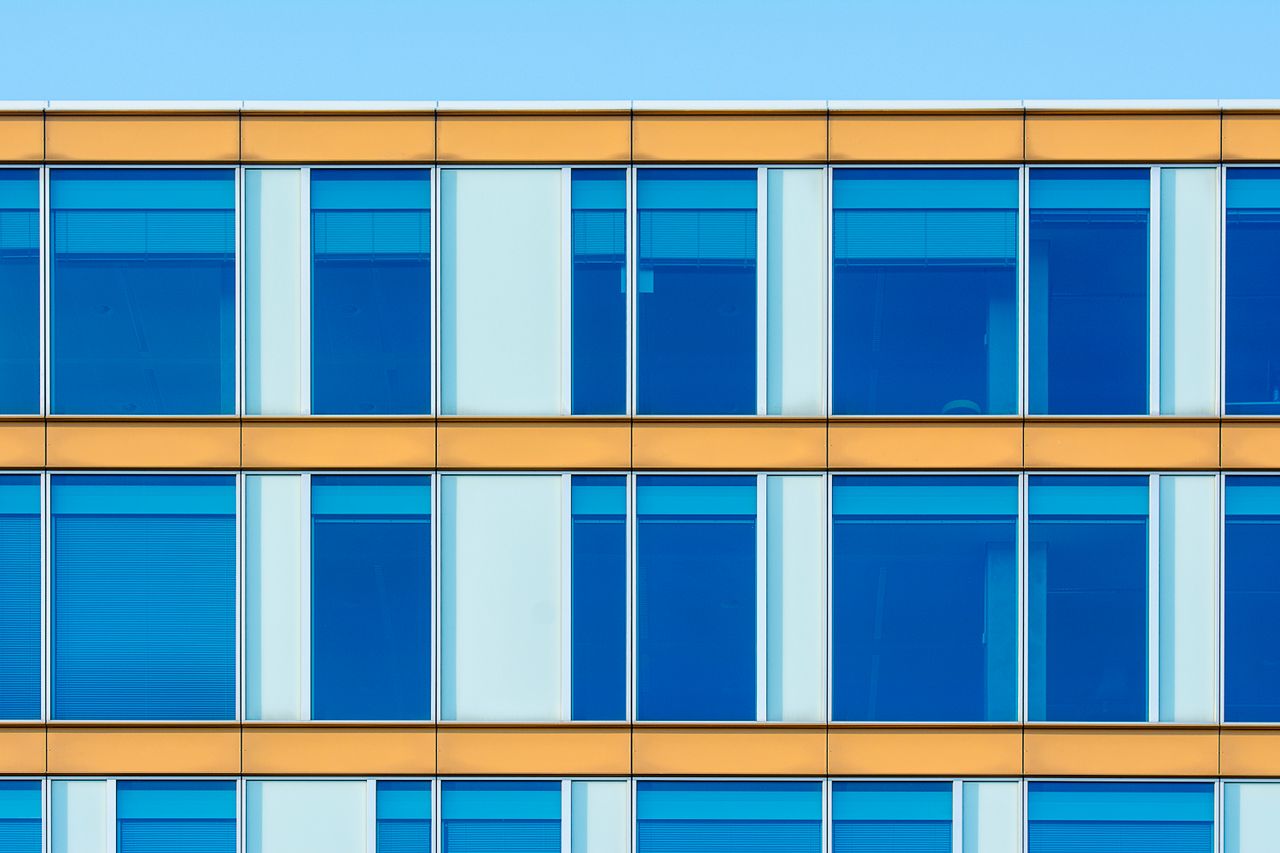 Contemporary office building facade showcasing blue windows and yellow structure.